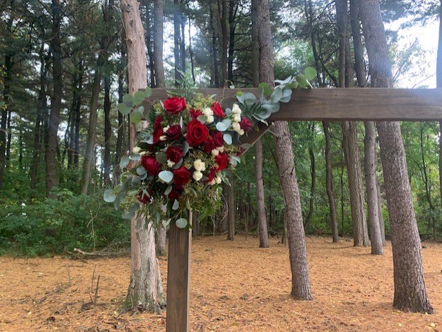 Burgundy and white rose swag on a wooden ceremony arbor