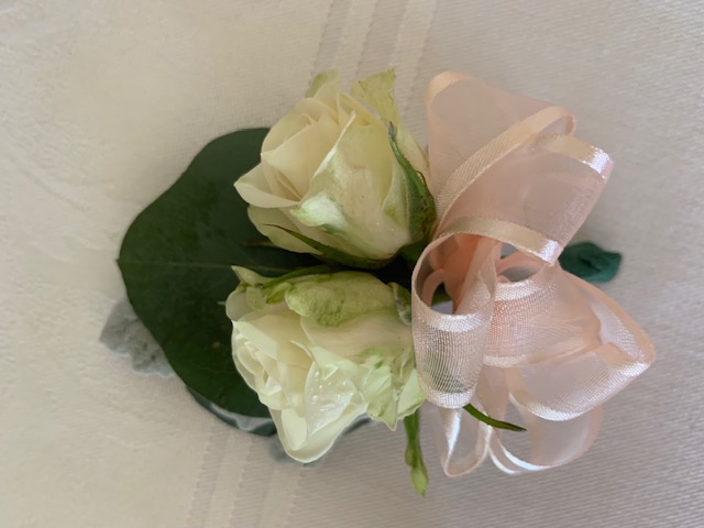 Double white sweetheart rose pin corsage with a pink bow