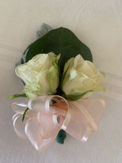 Double white sweetheart rose pin corsage with a pink bow
