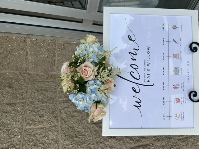 Light blue hydrangea and pink rose arrangement on a welcome sign