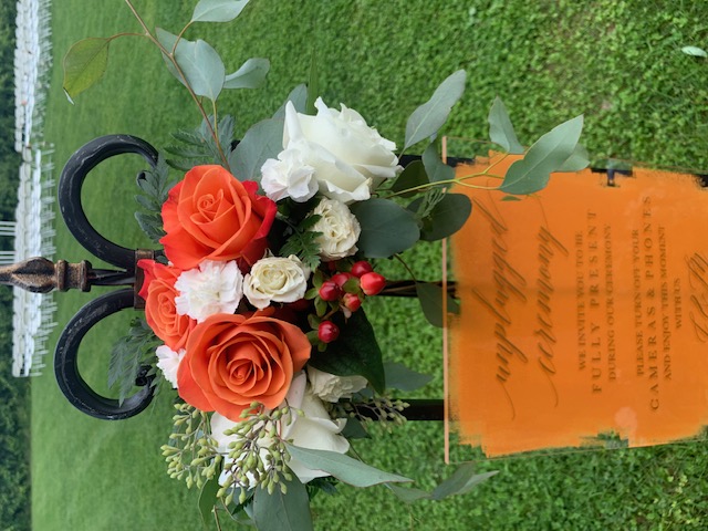 Orange rose, hypericum, and white rose welcome sign arrangement