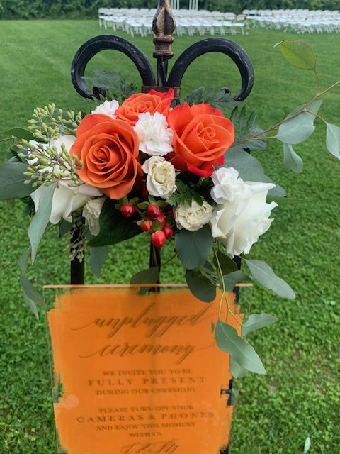 Orange rose, hypericum, and white rose welcome sign arrangement