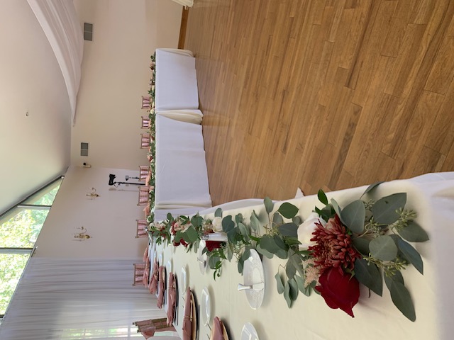 Red rose and greenery runner on a head table