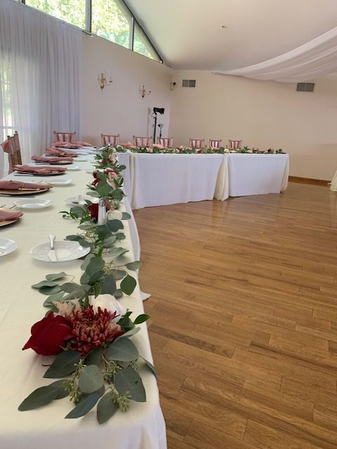 Red rose and greenery runner on a head table