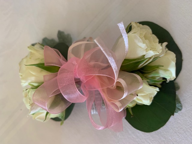 White sweetheart rose corsage with a pink bow