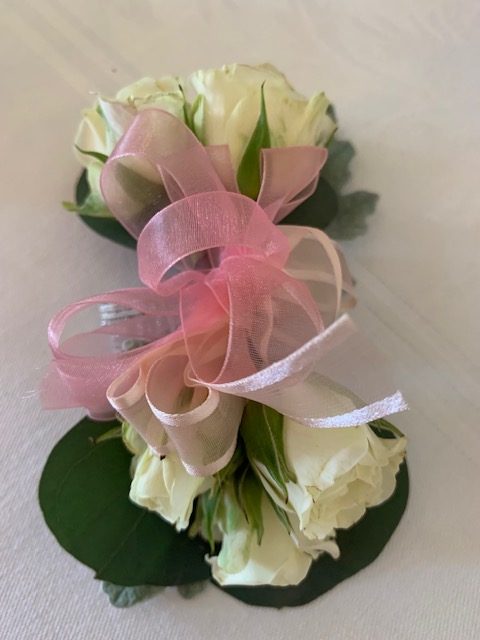 White sweetheart rose corsage with a pink bow